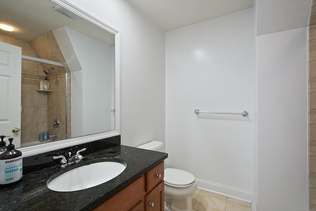 bathroom featuring toilet, vanity, tiled shower, and tile patterned flooring