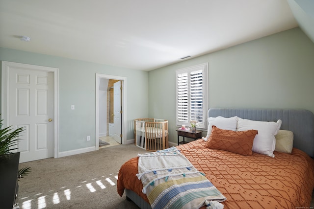 carpeted bedroom with ensuite bathroom and vaulted ceiling