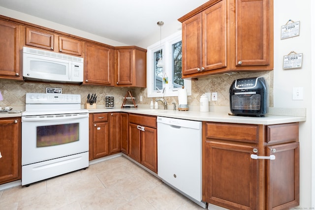 kitchen with hanging light fixtures, tasteful backsplash, sink, and white appliances