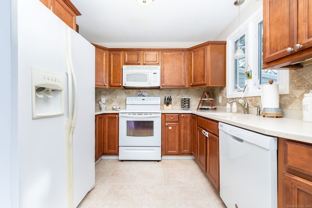 kitchen with sink, white appliances, backsplash, light tile patterned flooring, and decorative light fixtures