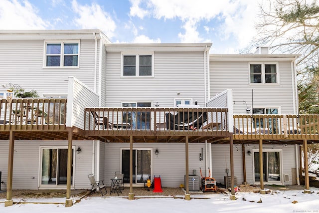 snow covered house featuring a wooden deck and central air condition unit