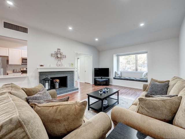 living room with recessed lighting, visible vents, vaulted ceiling, and light wood finished floors