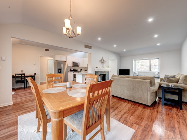 dining area featuring visible vents, lofted ceiling, recessed lighting, a fireplace, and light wood-type flooring