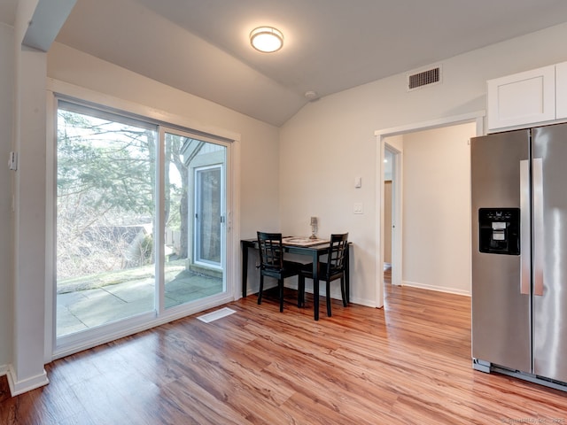 dining space with vaulted ceiling, light wood-style floors, visible vents, and baseboards