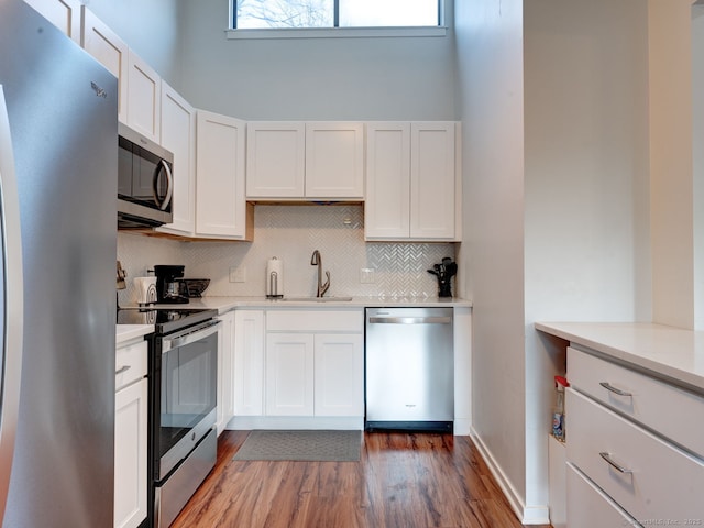 kitchen featuring tasteful backsplash, light countertops, appliances with stainless steel finishes, white cabinetry, and a sink