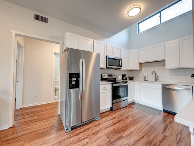 kitchen with visible vents, light wood-style flooring, light countertops, appliances with stainless steel finishes, and white cabinetry