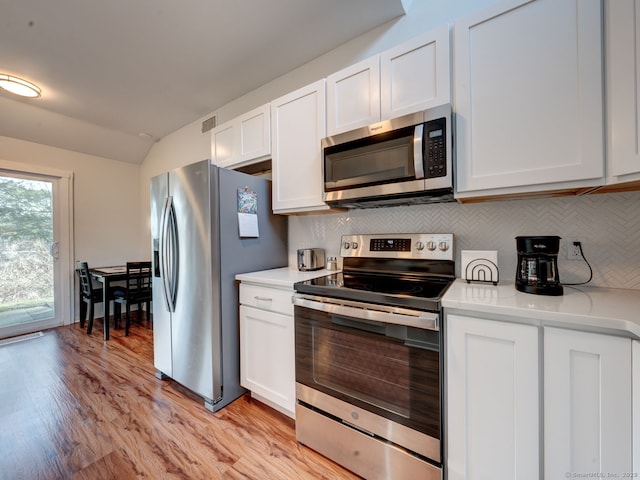 kitchen featuring light countertops, light wood-type flooring, decorative backsplash, stainless steel appliances, and white cabinetry