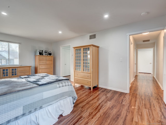 bedroom with visible vents, baseboards, and light wood finished floors