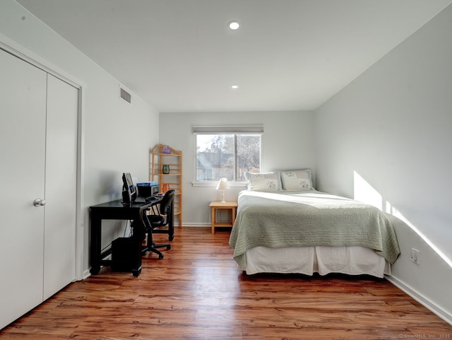 bedroom with wood finished floors, visible vents, baseboards, recessed lighting, and a closet