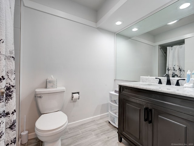 bathroom featuring vanity, baseboards, wood finish floors, recessed lighting, and toilet