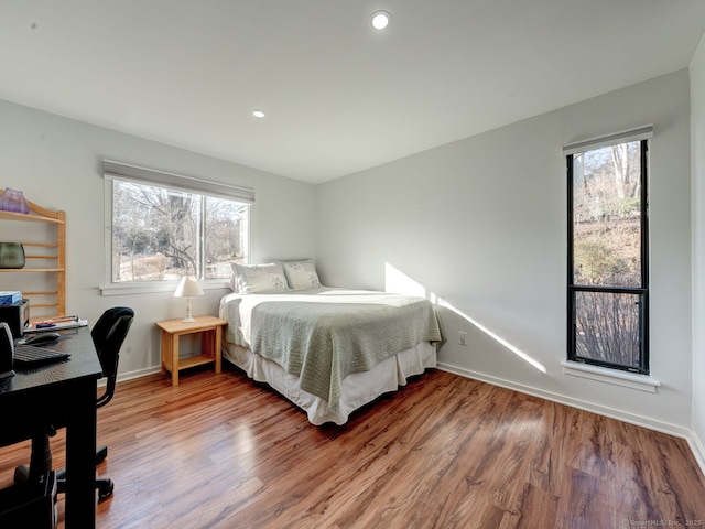 bedroom with multiple windows, baseboards, and wood finished floors