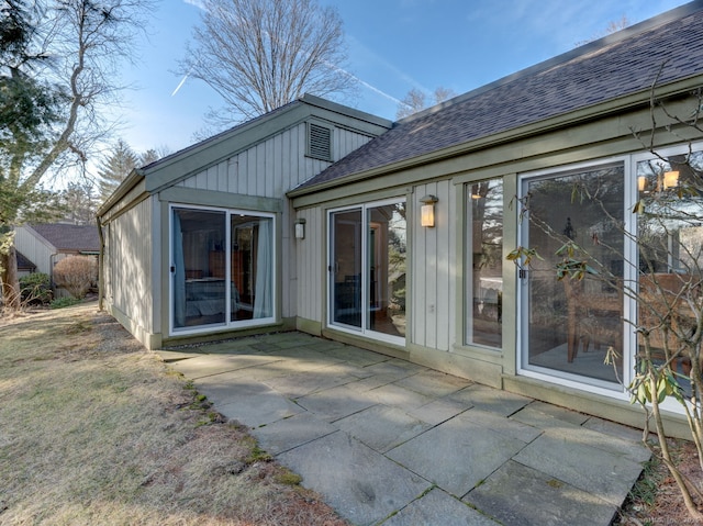 rear view of property featuring a patio and a shingled roof