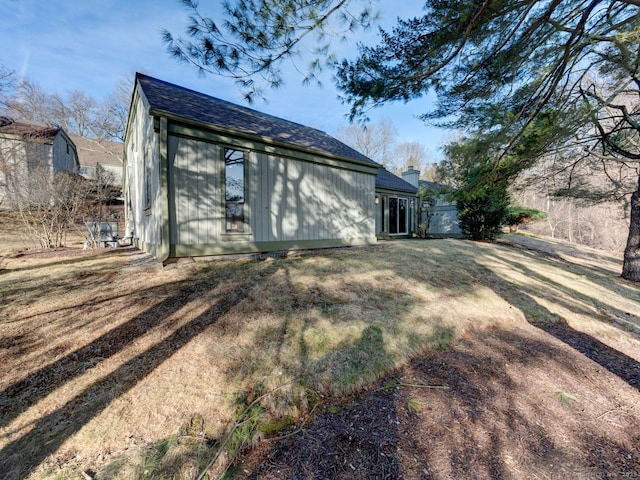 rear view of house with a chimney, a lawn, and a shingled roof