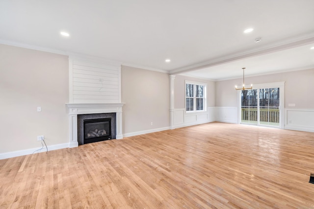 unfurnished living room featuring a fireplace, light hardwood / wood-style flooring, a notable chandelier, and ornamental molding