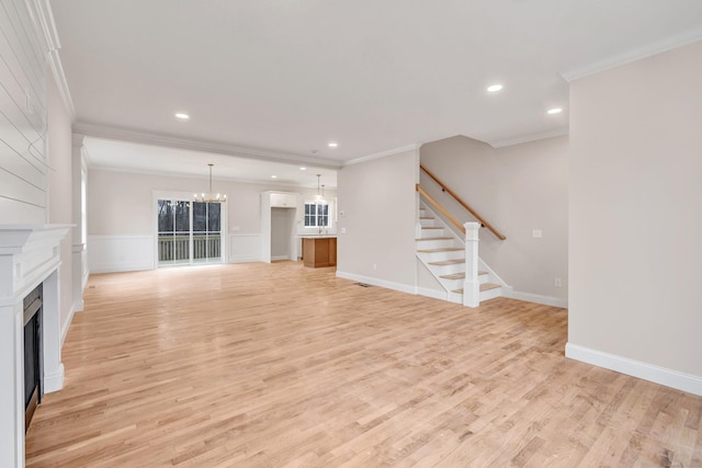 unfurnished living room featuring light hardwood / wood-style floors, crown molding, and a notable chandelier