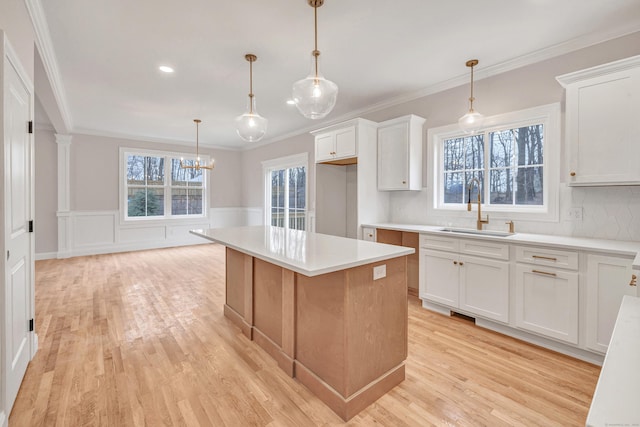 kitchen with sink, white cabinets, a center island, and hanging light fixtures