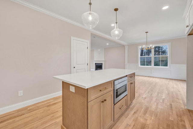 kitchen featuring a kitchen island, decorative light fixtures, stainless steel microwave, and ornamental molding