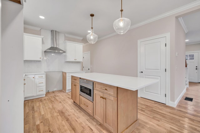 kitchen with stainless steel microwave, white cabinetry, a center island, wall chimney range hood, and decorative backsplash