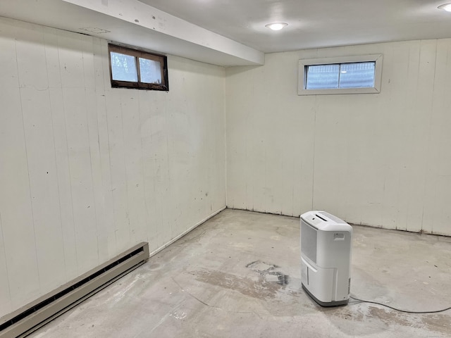 basement featuring a baseboard heating unit and wood walls