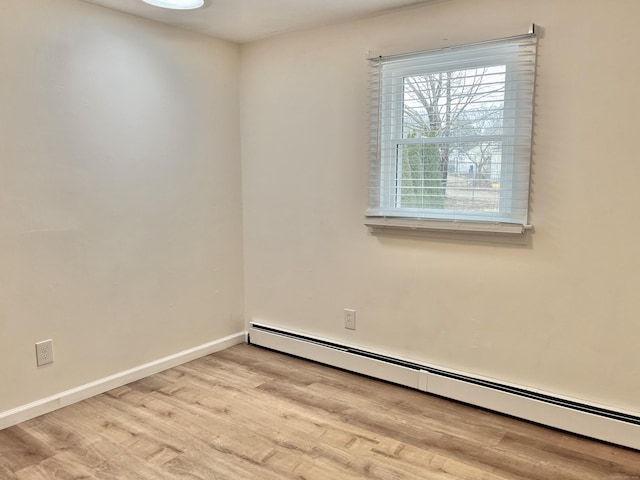 unfurnished room featuring a baseboard radiator and light wood-type flooring