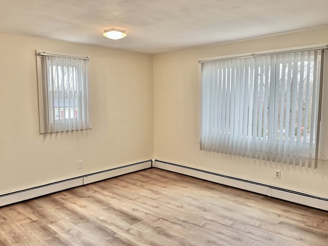 unfurnished room featuring baseboard heating and light hardwood / wood-style flooring