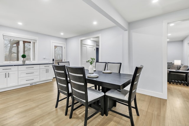 dining room featuring beam ceiling and light wood-type flooring