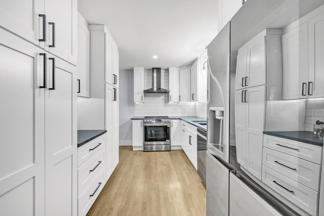 kitchen with stainless steel appliances, white cabinets, and wall chimney exhaust hood