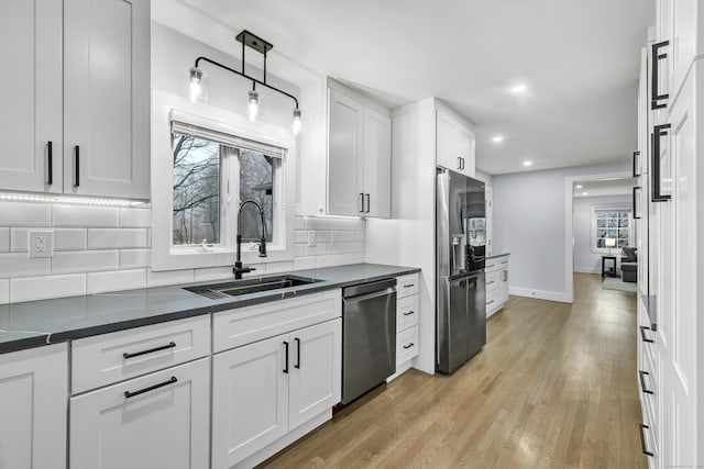 kitchen with pendant lighting, sink, white cabinets, and appliances with stainless steel finishes