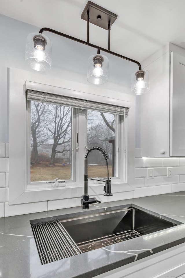 room details with white cabinetry, sink, and backsplash