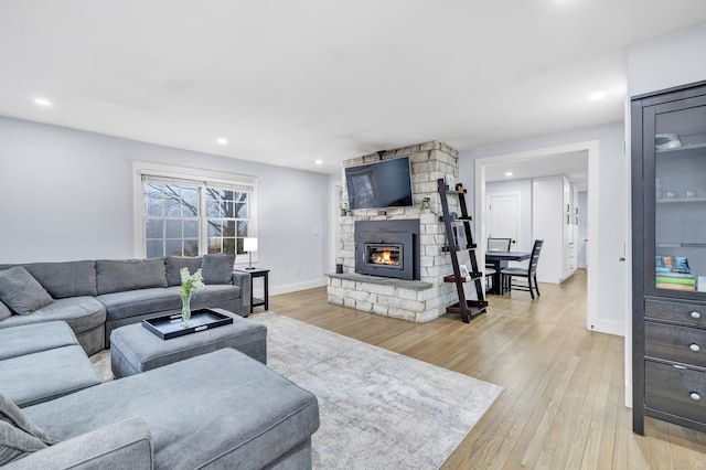 living room featuring a stone fireplace and light hardwood / wood-style floors