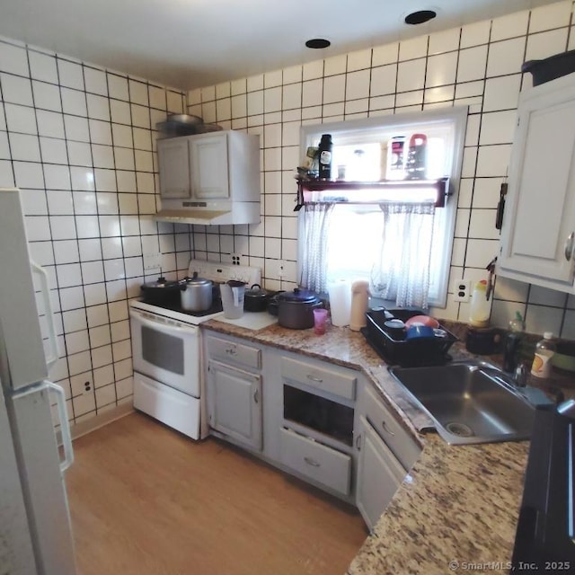 kitchen featuring white cabinets, white appliances, light hardwood / wood-style floors, and sink