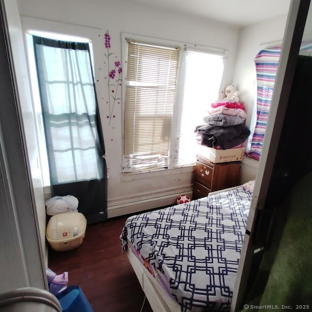 bedroom with baseboard heating and dark hardwood / wood-style flooring