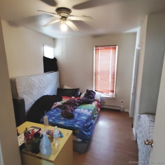 bedroom with a baseboard radiator, hardwood / wood-style floors, and ceiling fan