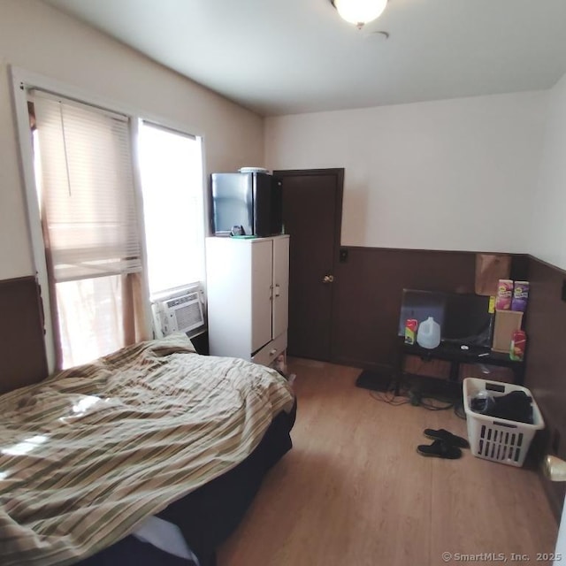 bedroom with light hardwood / wood-style floors and stainless steel fridge