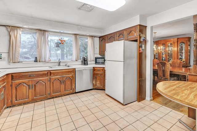 kitchen featuring stainless steel dishwasher, sink, white refrigerator, and light tile patterned flooring