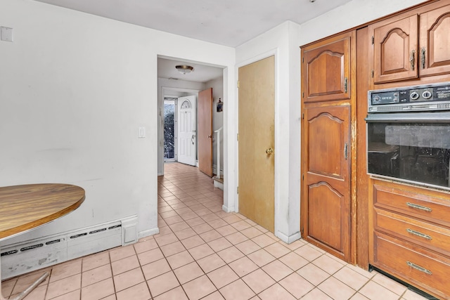 kitchen featuring light tile patterned floors, a baseboard radiator, and oven