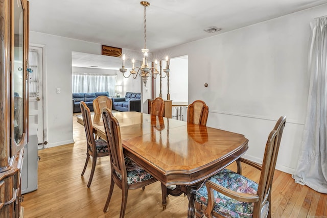 dining room with light wood-type flooring and a notable chandelier