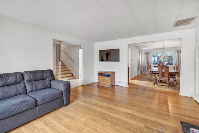 living room with baseboard heating, a chandelier, and light wood-type flooring