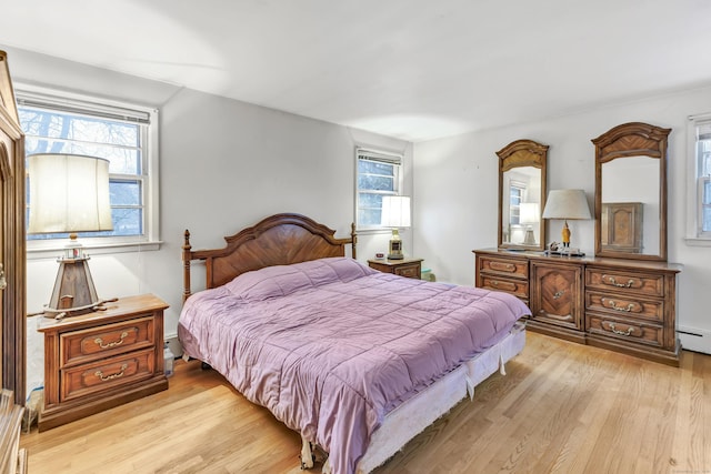 bedroom with a baseboard radiator and light wood-type flooring