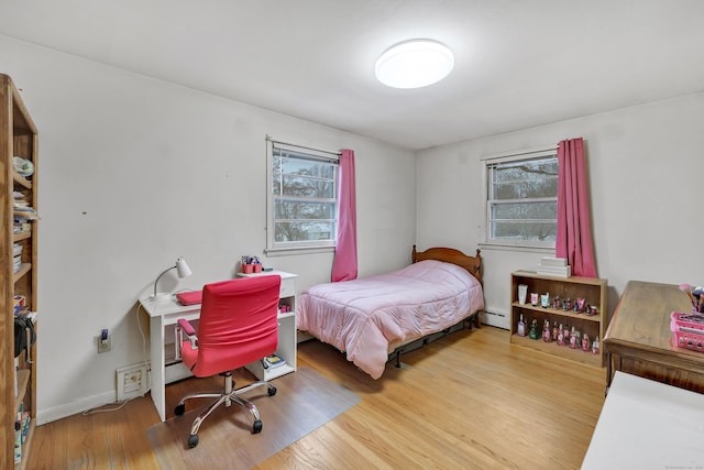 bedroom featuring a baseboard heating unit and hardwood / wood-style floors