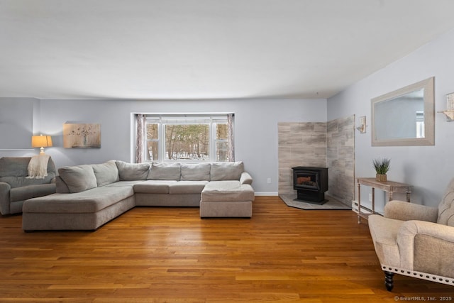 living room featuring light hardwood / wood-style flooring, a baseboard radiator, and a wood stove