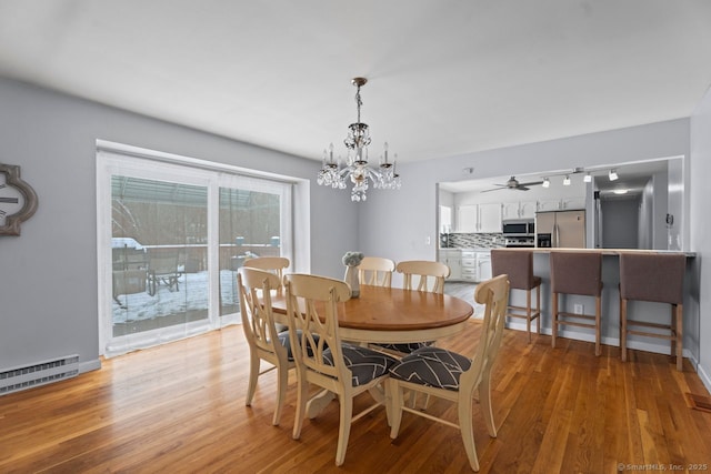 dining room featuring a baseboard heating unit, a chandelier, and light wood-type flooring