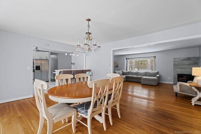 dining room featuring hardwood / wood-style floors, a tile fireplace, and a chandelier