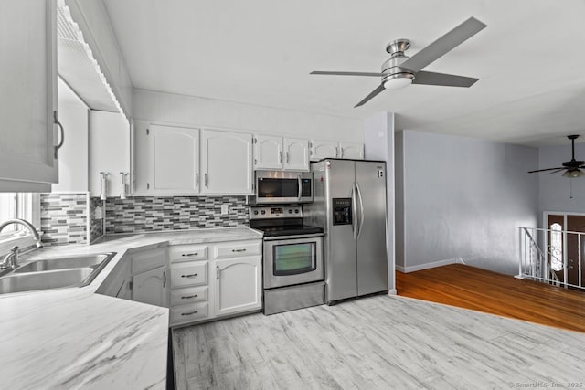 kitchen with sink, white cabinets, backsplash, stainless steel appliances, and light hardwood / wood-style flooring