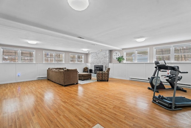 exercise area with a wealth of natural light, light hardwood / wood-style floors, and baseboard heating