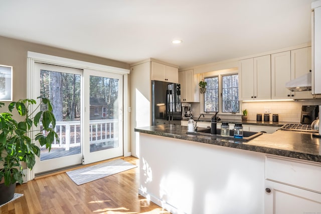 kitchen featuring kitchen peninsula, black appliances, white cabinetry, and light hardwood / wood-style floors