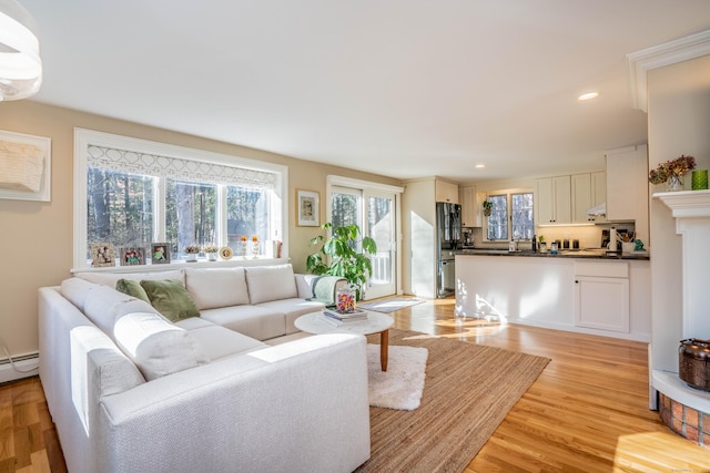 living room with baseboard heating and light hardwood / wood-style floors