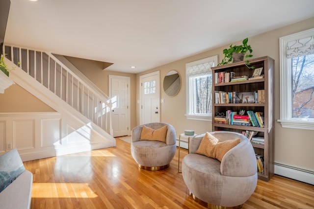 sitting room with a baseboard radiator, light wood-type flooring, and a wealth of natural light