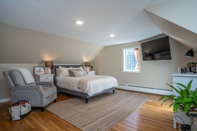 bedroom with baseboard heating, hardwood / wood-style flooring, and vaulted ceiling