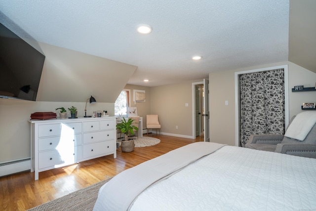 bedroom with light hardwood / wood-style floors, a baseboard radiator, a textured ceiling, and lofted ceiling